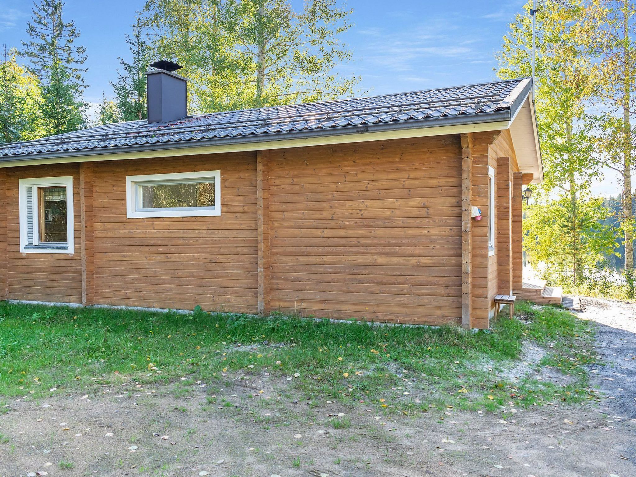 Ein kleines Holzhaus mit einem Ziegeldach, einem Schornstein und einem Fenster mit Fensterläden.
