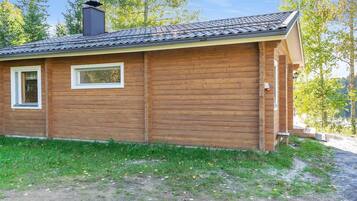 Ein kleines Holzhaus mit einem Ziegeldach, einem Schornstein und einem Fenster mit Fensterläden.