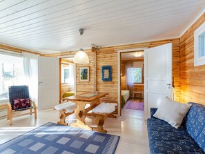 A cabin interior with a wooden interior, a dining table, a sofa, and a chair. - Jussinlahti, vaikon loma 6 by Interhome (Kaavi)