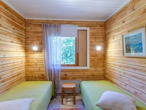 A cabin with two single beds, a small table, and a window with curtains.