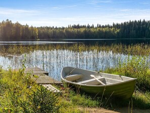 A rowboat on a wooden dock by a calm lake with dense forest in the background. - Jussinlahti, vaikon loma 6 by Interhome (Kaavi)