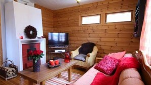 A cozy living room with a fireplace, a television, a sofa, and a chair. - Vacation home Monaco by Interhome (Asikkala)