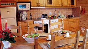 A wooden kitchen with a dining table set for four, equipped with chairs and a centerpiece. - Vacation home Monaco by Interhome (Asikkala)