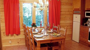 A wooden cabin interior with a dining table set for four, a refrigerator, and a kitchen area. - Vacation home Monaco by Interhome (Asikkala)