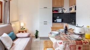 A compact living space with a kitchenette, a dining area, and a sofa. - Plein Soleil by Interhome (La Toussuire)