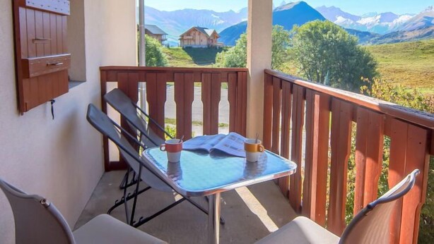 A balcony with a table and chairs, overlooking a mountainous landscape. - Plein Soleil by Interhome (La Toussuire)