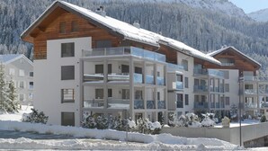 Een hotel met meerdere verdiepingen en balkons, met een besneeuwde berg op de achtergrond.