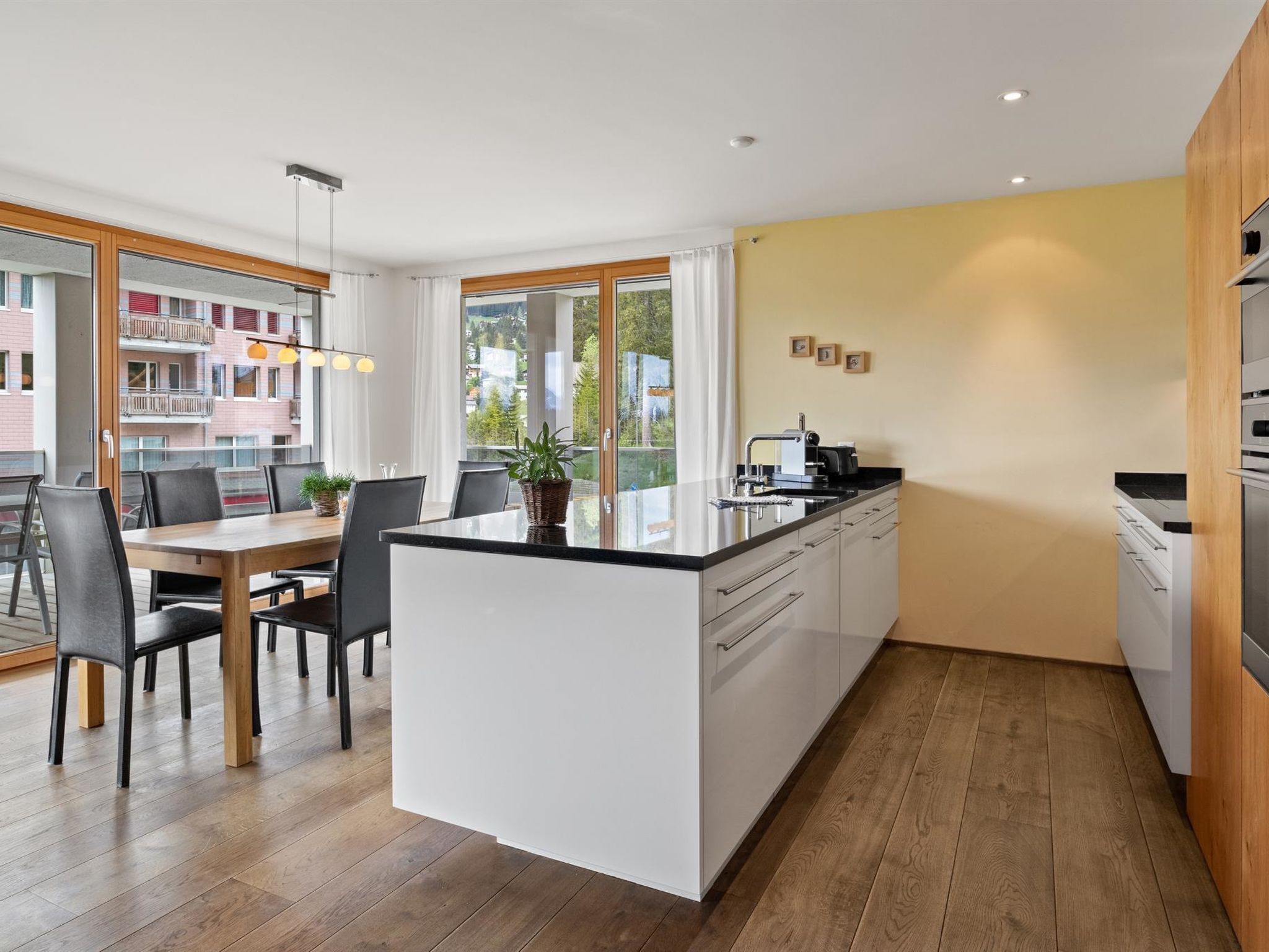 A modern kitchen with a central island, white cabinetry, and a view of the outside.