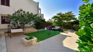 A patio with a swing set, a small seating area, and a garden bed. - Apartment Marija by Interhome (Pag/Dinjiška)