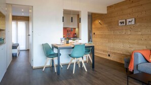 Ein modernes Interieur mit Essbereich, Küche und einer gemütlichen Sitzecke mit Holzwand und Kamin.