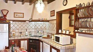 A kitchen with a tiled backsplash, a microwave, a sink, and a dining area set for four. - Camino La Candelaria by Interhome (La Orotava)