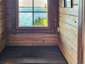 Habitación de cabaña de madera con un amplio ventanal con vistas a un lago y un bosque.