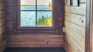 Une pièce de cabane en bois avec une grande fenêtre donnant sur un lac et une forêt.