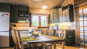 Un intérieur en bois comprenant une table à manger, des chaises, un réfrigérateur et des placards.