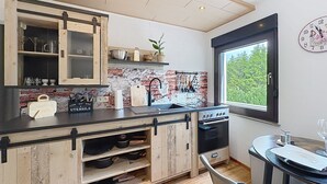 Una cocina con salpicadero de ladrillo, armarios de madera, un lavamanos y una ventana con vistas.