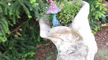 Una escultura de piedra de una mano sosteniendo un hongo con gorro rojo y tallo azul.