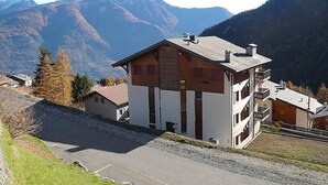 A multi-story building with a sloped roof, located in a mountainous area with visible peaks in the background. - Hauts de Morthey No 33 by Interhome (Ovronnaz)