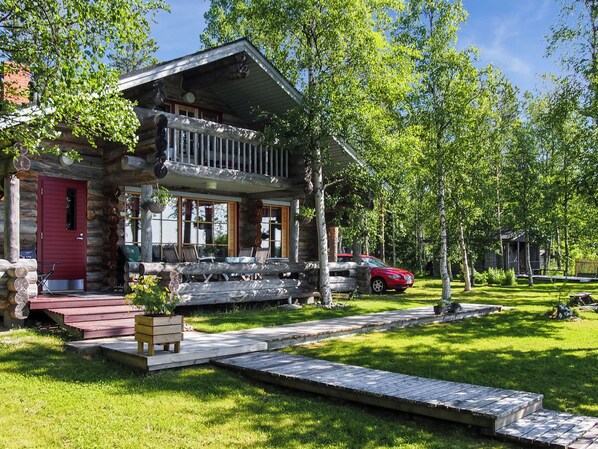 A log cabin with a porch, a red door, and a car parked in the driveway. - Alakitkajärvi, takkusalmi by Interhome (Kuusamo)