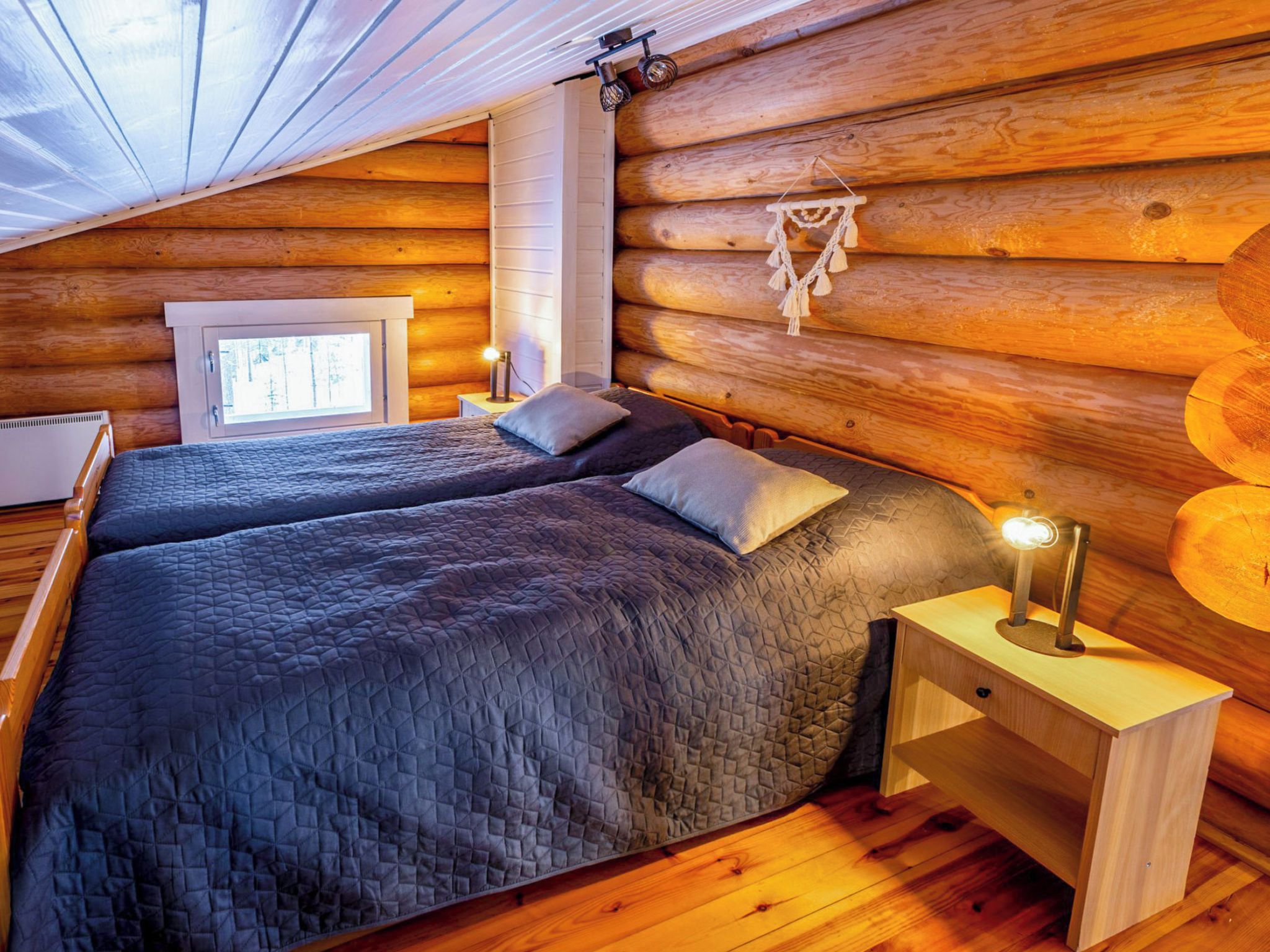 Une chambre à coucher située dans une cabane en rondins, avec un lit, des tables de chevet et une fenêtre.