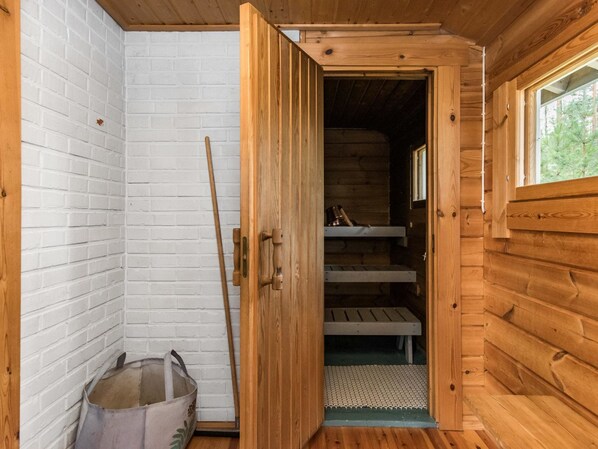 A wooden cabin with a white brick wall, a wooden door, and a window.