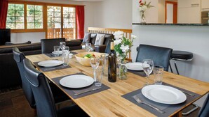 Comedor con una mesa de madera dispuesta para cuatro personas, rodeado de sillas negras.