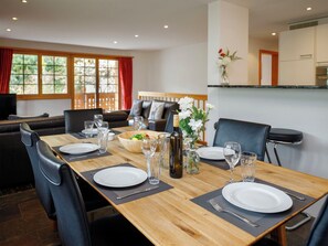 Un coin repas avec une table en bois dressée pour quatre personnes, entourée de chaises noires.
