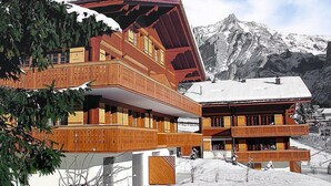 Un edificio de madera de varios pisos con balcones, con una montaña nevada al fondo.
