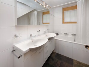 Une salle de bain moderne avec deux lavabos, une baignoire et une douche.