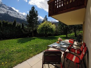 Une terrasse extérieure avec une table dressée pour le repas, des chaises et une vue sur un paysage montagneux.
