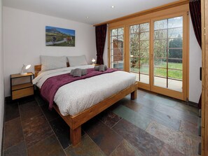 Une chambre à coucher avec un grand lit, une table de chevet, une lampe de chevet, une fenêtre avec des rideaux et un tableau au mur.