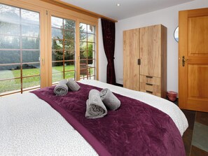 Une chambre à coucher avec un lit, une grande fenêtre, une armoire et une porte.