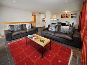 Un salon moderne avec deux canapés en cuir, une table basse en bois et un tapis rouge à motifs.