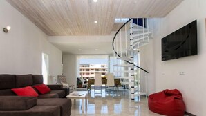 Ein geräumiger Wohnbereich mit moderner Treppe, einem Flachbildfernseher und einem roten Sitzsack.