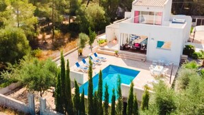 Eine moderne Villa mit Swimmingpool, Sitzgelegenheiten im Freien und Blick auf den umliegenden Wald.