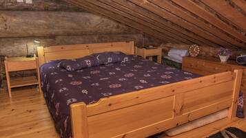 Een gezellig slaapkamer onder het dak met een houten bed, een bureau en een nachtkastje.