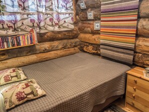 A cozy log cabin room with a bed, pillows, a bookshelf, and a wall with framed pictures. - Salmikangas h2 by Interhome (Kuusamo)
