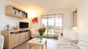 Een moderne woonkamer met een bank, een salontafel, een televisie en een boekenkast.