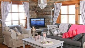 A cozy living room with a stone wall, a television, a sofa, a coffee table, and a fireplace.
