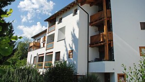 A modern multi-story building with balconies, surrounded by greenery. - Apartment Girun by Interhome (Flims)