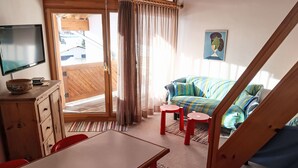 A cozy room with a wooden desk, a television, a sofa, and a staircase. - Apartment Girun by Interhome (Flims)