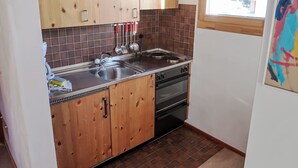 A kitchen with wooden cabinets, a stainless steel sink, and a black oven. - Apartment Girun by Interhome (Flims)