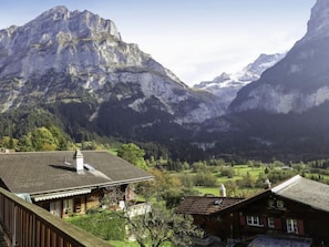 A mountain landscape with a valley, a wooden house with a sloped roof, and a small building with a chimney. - Ahornen by Interhome (Grindelwald)