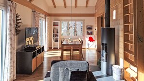 Ein gemütliches Wohnzimmer mit Fernseher, Holzmöbeln, einem Essbereich und einem Kamin.