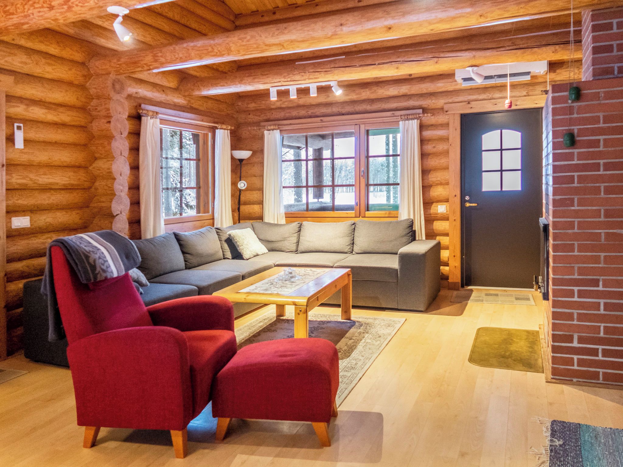 A log cabin interior with a sofa, armchair, and coffee table.