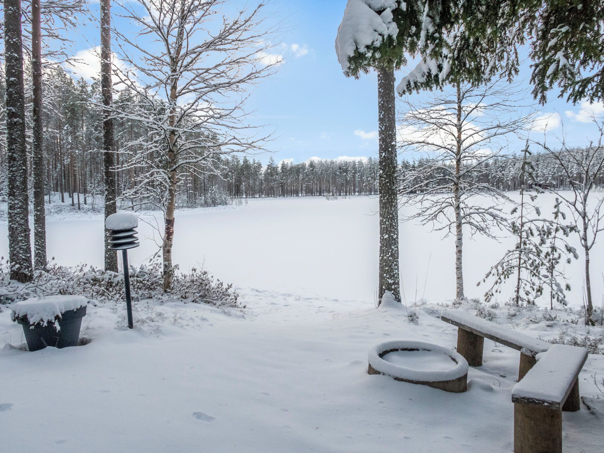 A snow-covered outdoor area with benches and a fire pit.