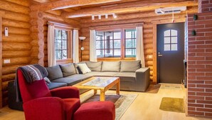 Ein Holzblockhaus-Interieur mit einer Couch, einem Sessel und einem Couchtisch.