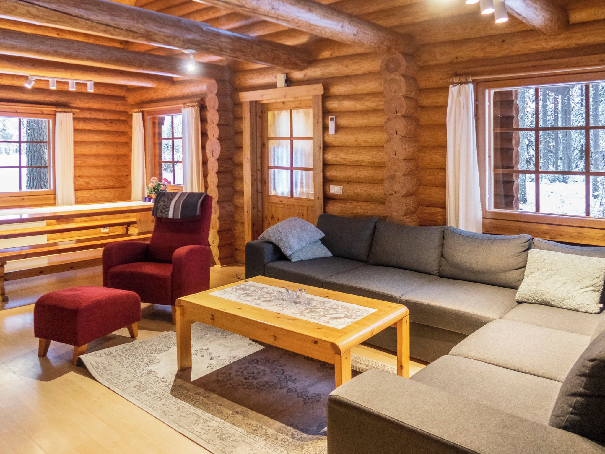 A cozy log cabin interior with a sofa, armchair, and a wooden coffee table.