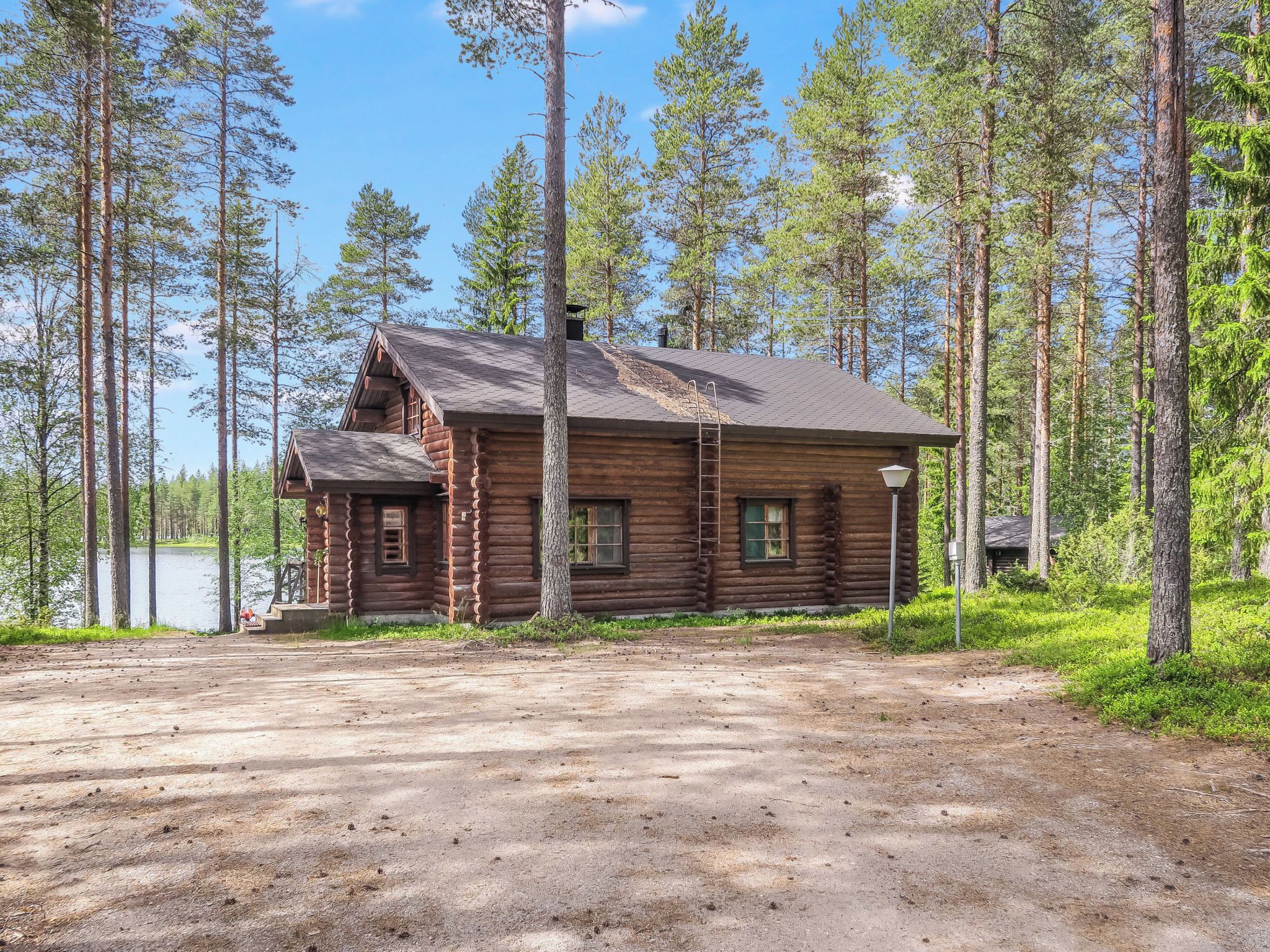 A log cabin with a porch, a chimney, and a view of a lake.