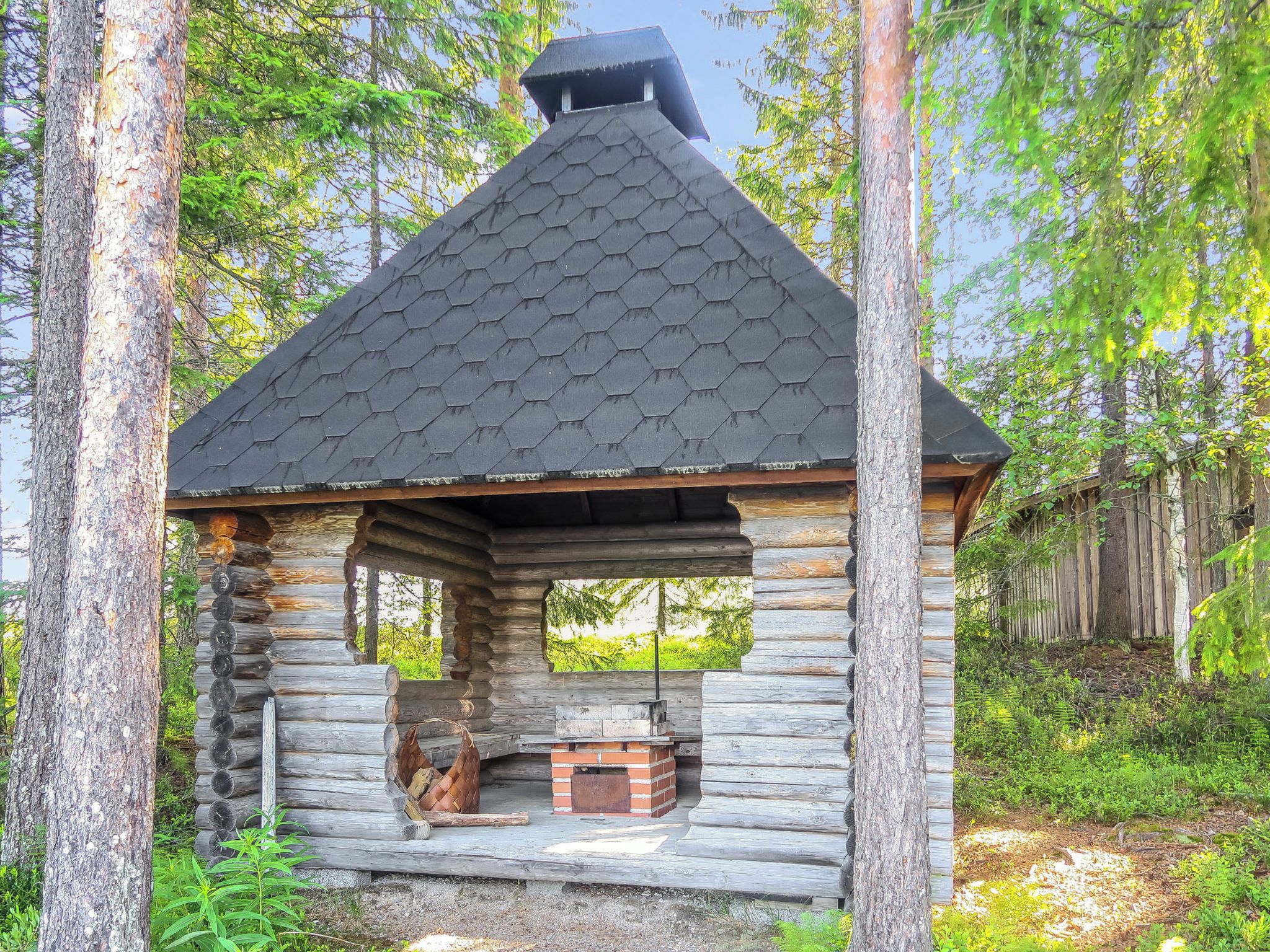 A log cabin with a hexagonal roof, a chimney, and a brick fireplace.