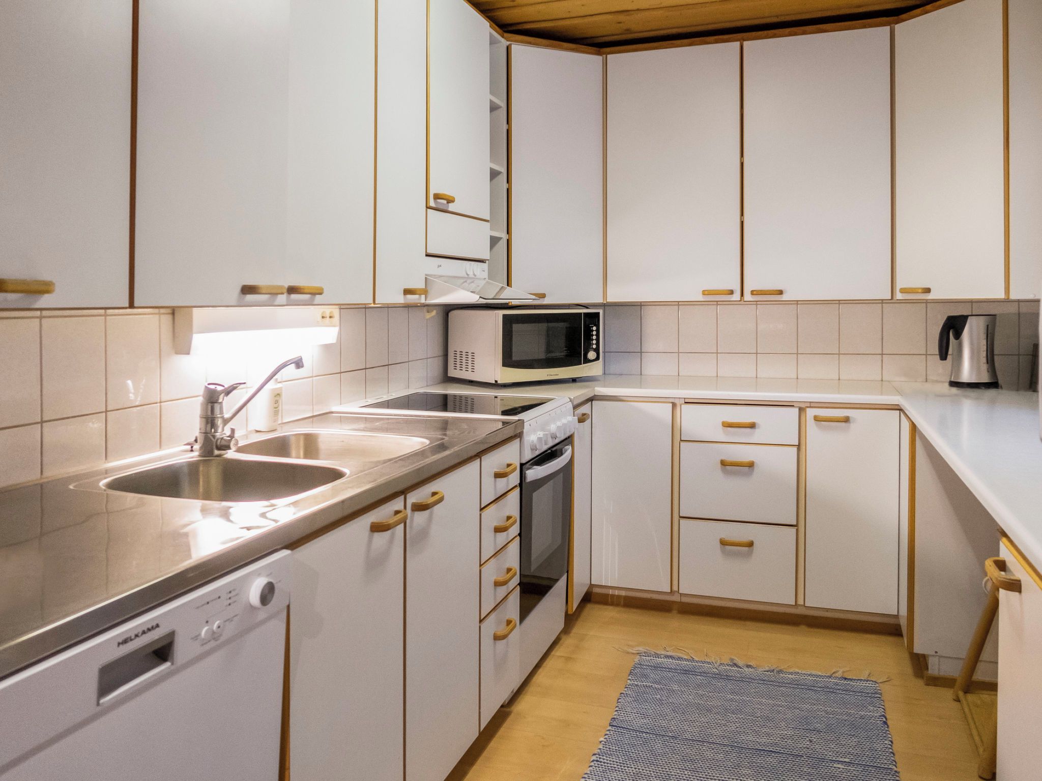 A modern kitchen with white cabinets, stainless steel appliances, and a wooden floor.